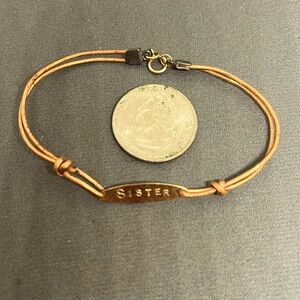 Copper bracelet stamped “sister”.